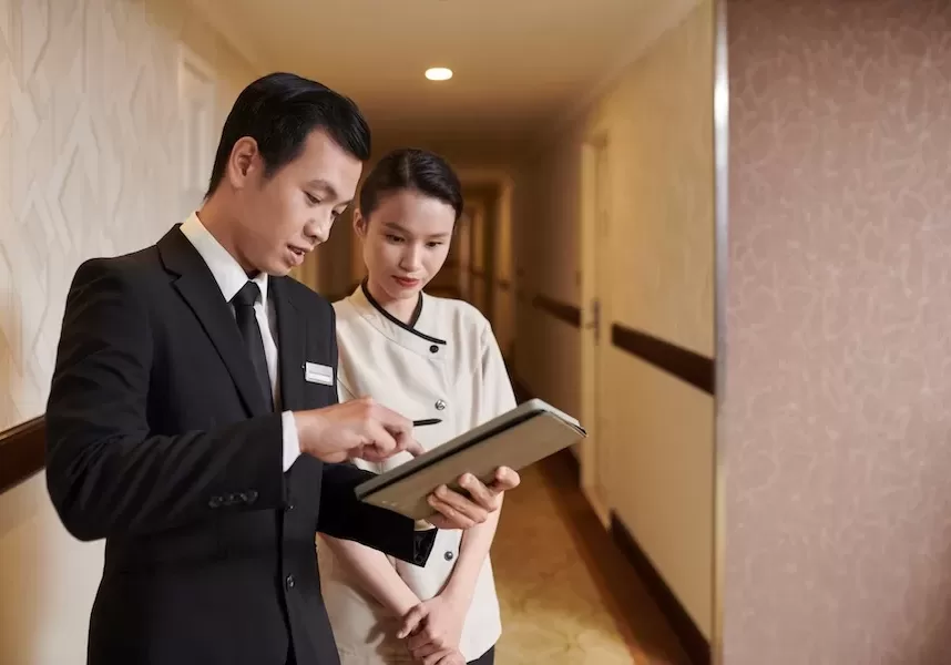 Hotel manager showing maid what rooms she needs to clean for guests