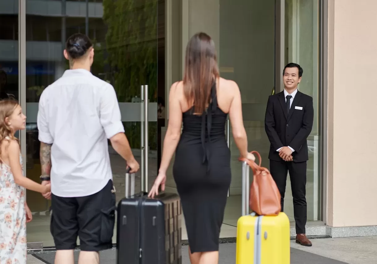 Smiling concierge welcoming guests at hotel entrance